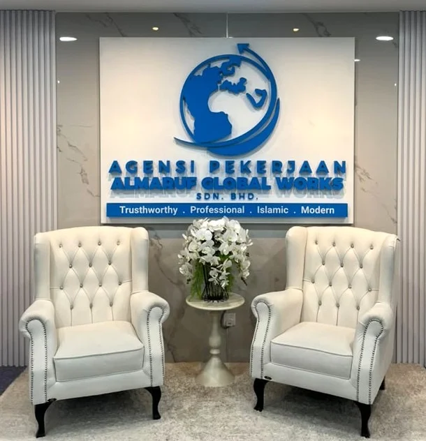 The reception at the Almaruf office: the agency's wall sign above two white armchairs and a vase of orchids